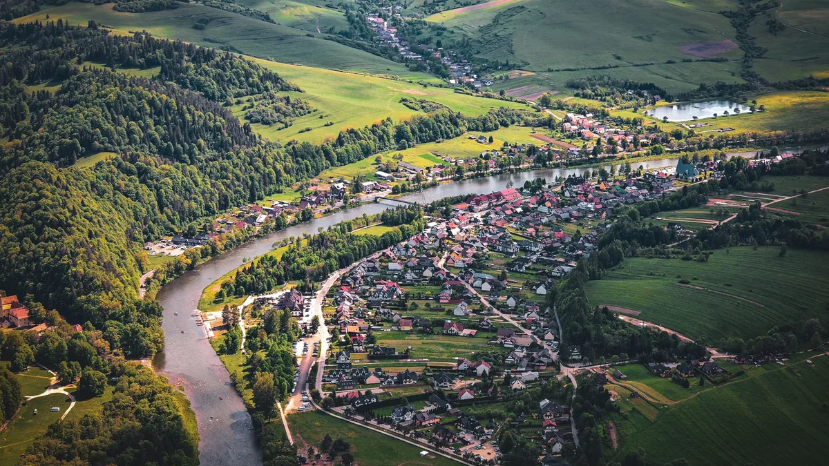 Scenic aerial view of Červený Kláštor village nestled in lush greens and flowing river in Slovakia.